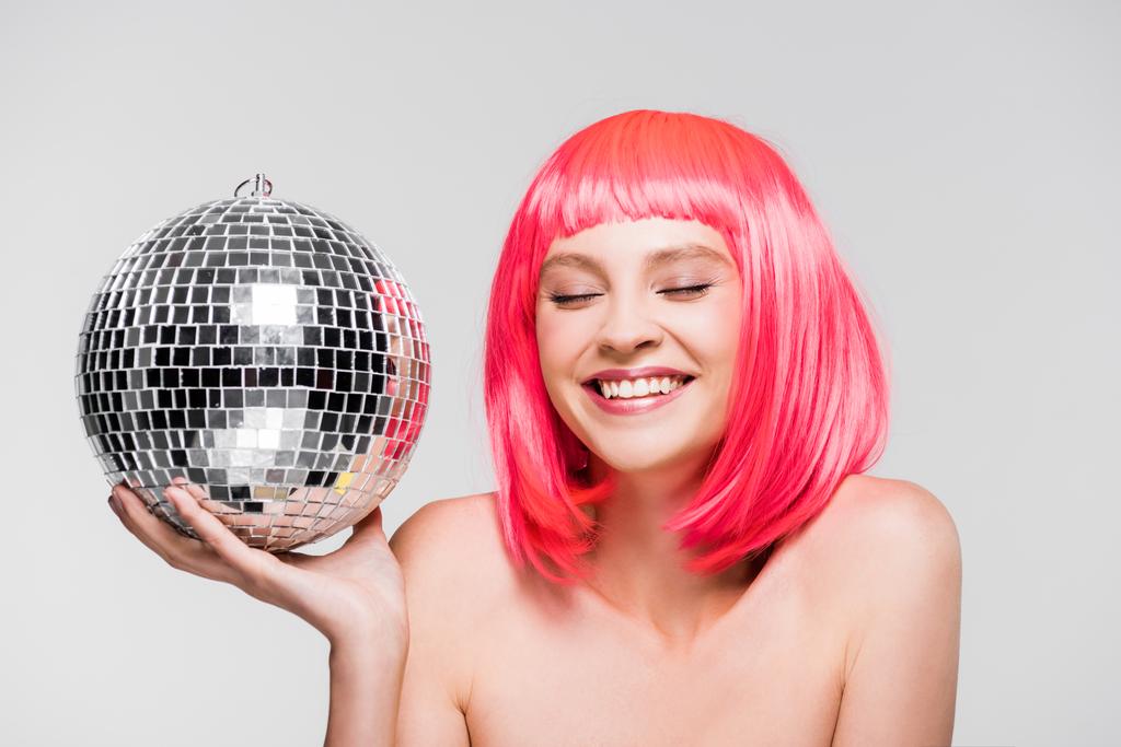 attractive happy girl in pink wig holding disco ball, isolated on grey - Photo, Image