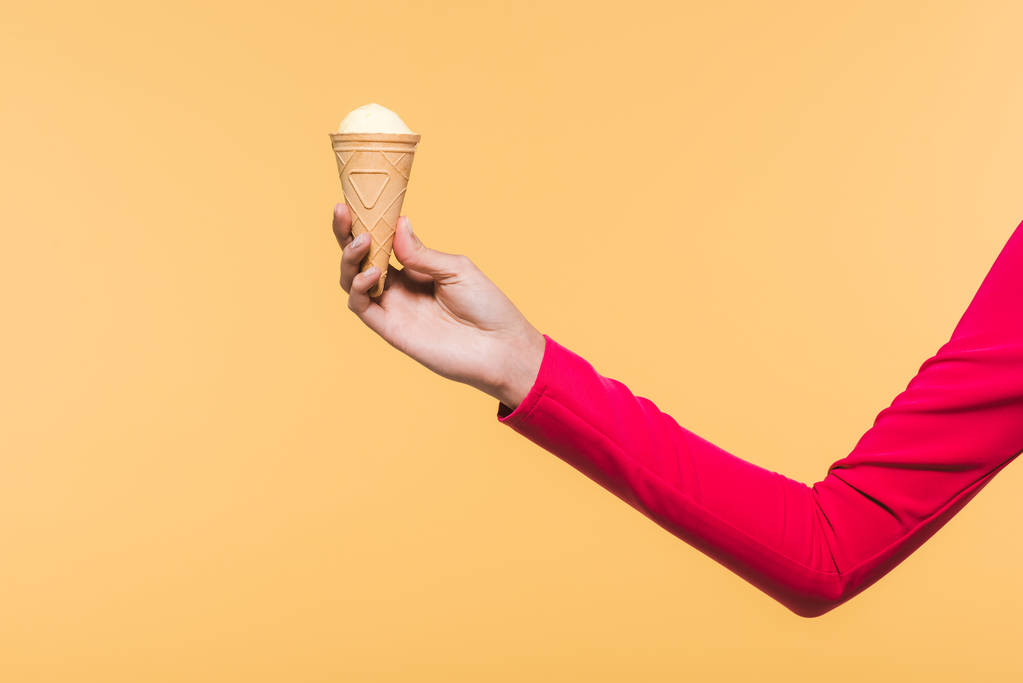 částečný pohled na ženu, která drží zmrzlinu v ruce, izolovaná na žluté - Fotografie, Obrázek