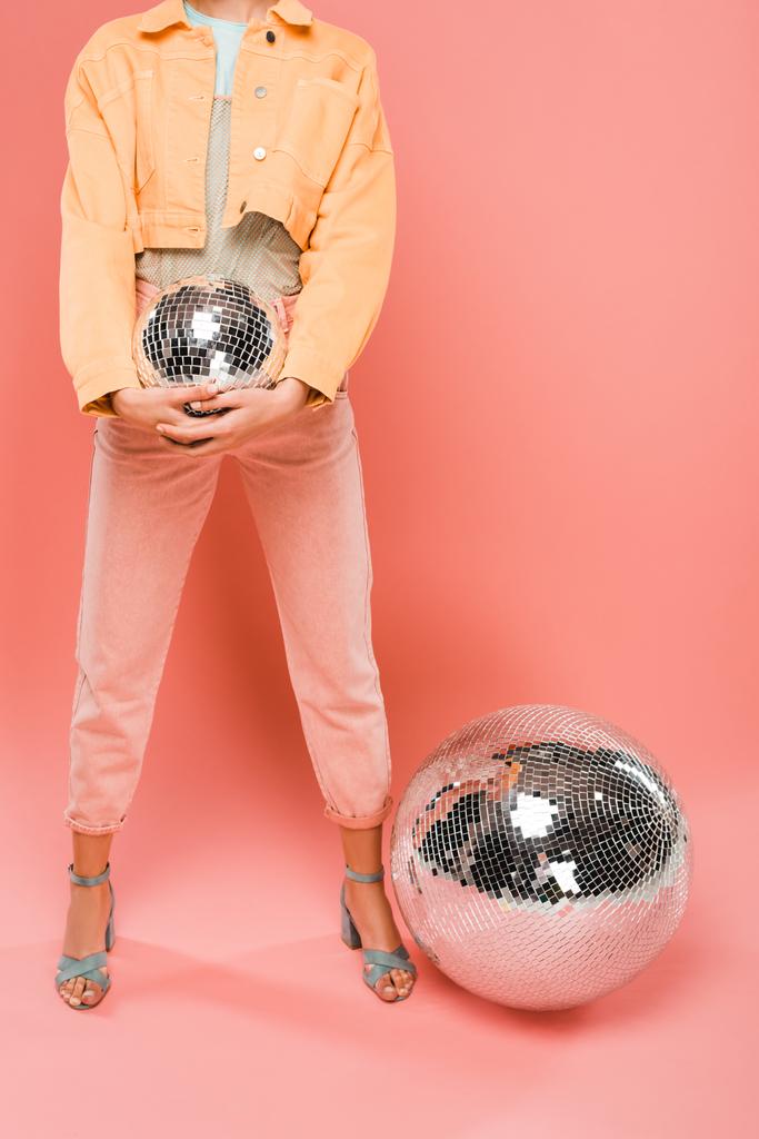 bijgesneden weergave van modieuze meisje houden disco bal op roze - Foto, afbeelding