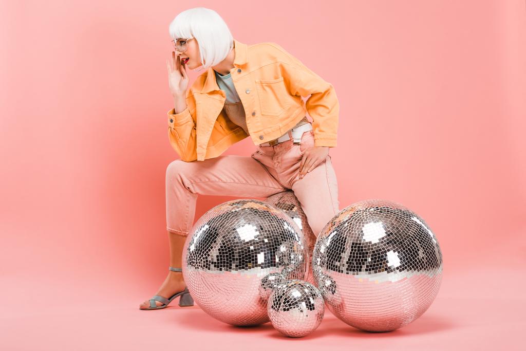 стильная девушка в белом парике позирует с шарами диско на розовом
 - Фото, изображение