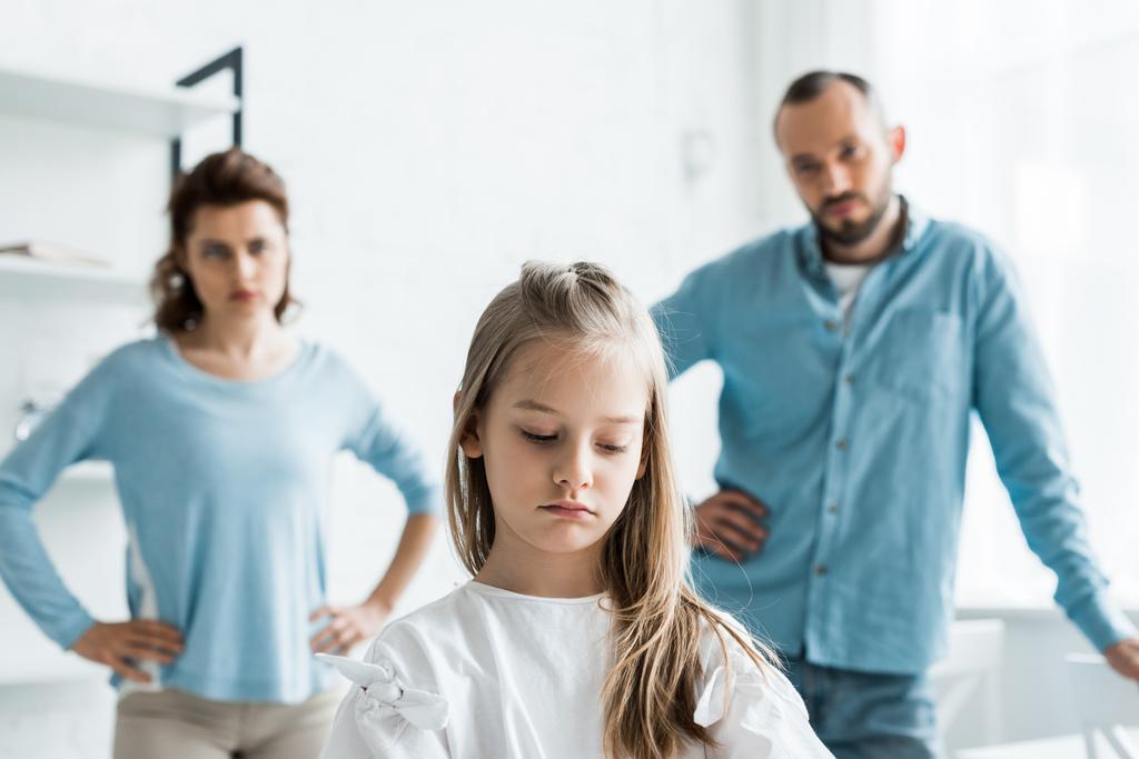 valikoiva painopiste järkyttynyt lapsi lähellä surullisia vanhempia seisoo kotona
  - Valokuva, kuva