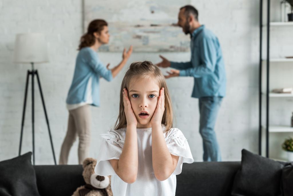 口論の親の近くに立っている間、ショックを受けた子供の顔に触れる選択的な焦点  - 写真・画像