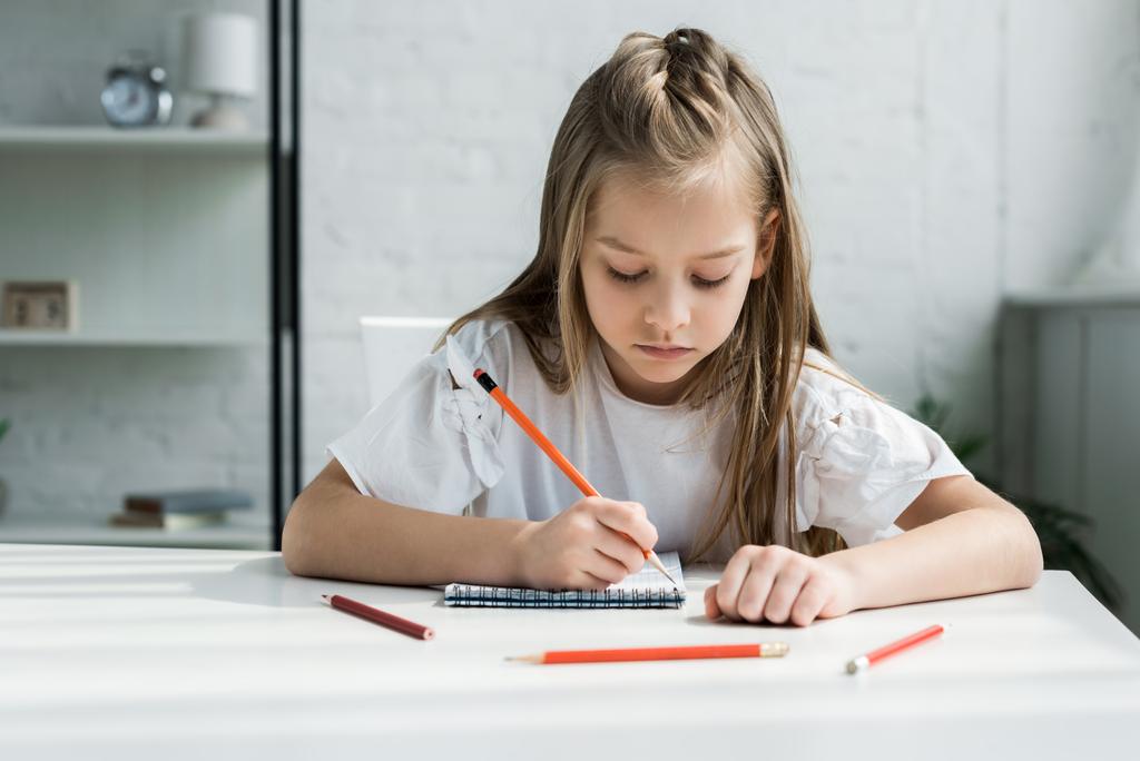 aranyos gyerek gazdaság ceruza írás közben a notebook otthon  - Fotó, kép