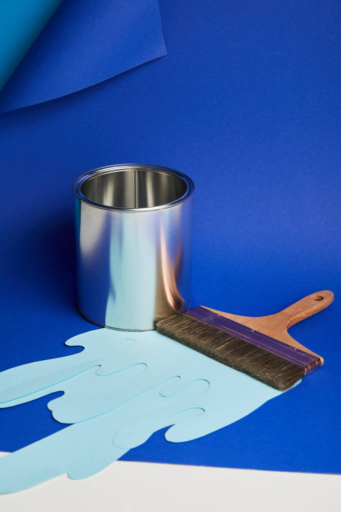 kovová lesklá plechovka, kartáček a kapající papír na světle modrém pozadí - Fotografie, Obrázek