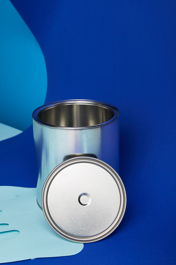 lata de plata sobre papel goteando pintura cortada sobre fondo azul brillante
 - Foto, imagen