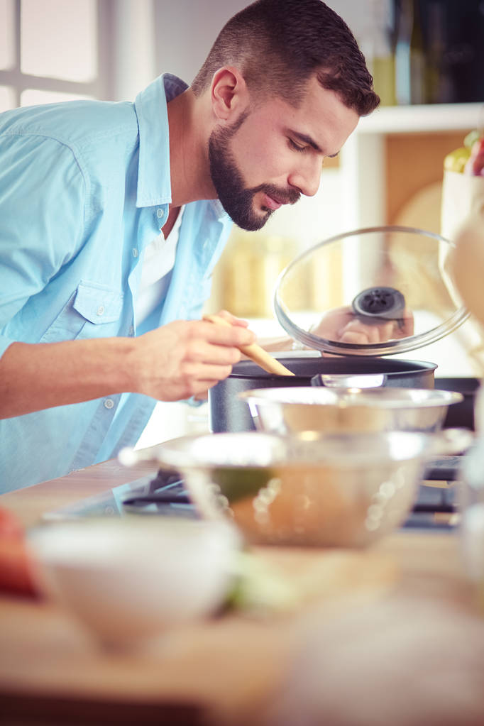 L'uomo segue la ricetta su tavoletta digitale e cucina cibo gustoso e sano in cucina a casa - Foto, immagini