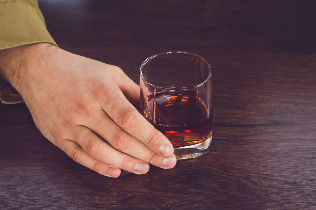 A man holding a glass of whiskey. Male hands holding a glass cup - Photo, Image