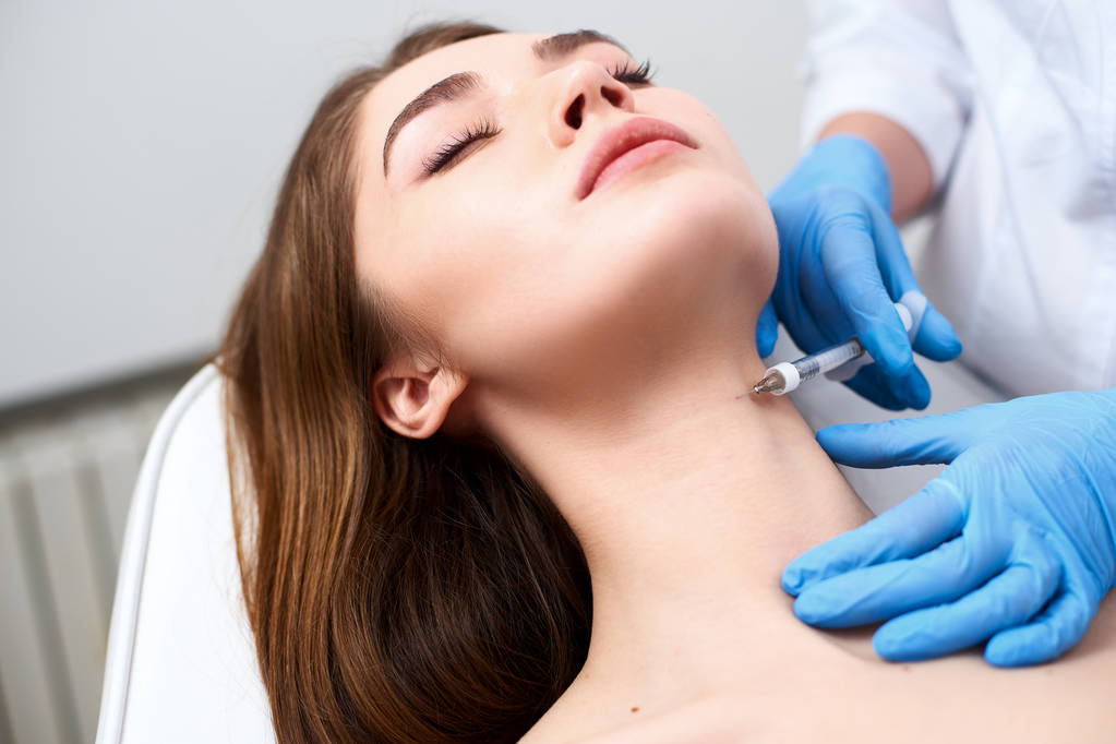 Beautician doctor with botulinum toxin syringe making injection to platysmal bands. Neck rejuvenation mesotherapy. Anti-aging treatment and face lift in cosmetology clinic. Patient lying on chair. - Photo, Image