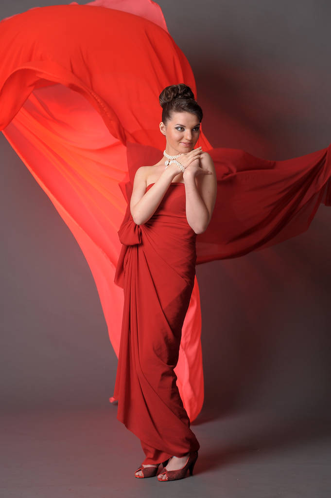 girl in a red dress  in the studio and flowing fabric - Photo, Image