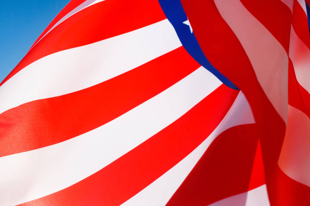 Amerikan lippu tuulessa sinistä taivasta vasten
 - Valokuva, kuva