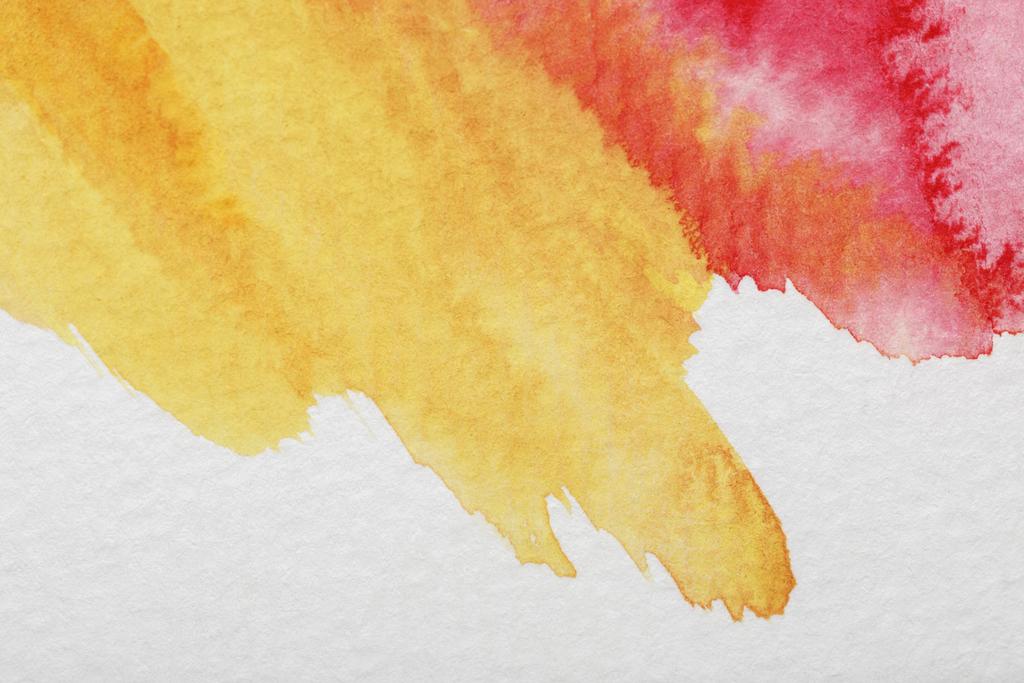close up view of yellow and red mixed watercolor paint spills on white background - Photo, Image