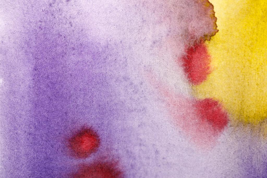 закрыть вид на разливы желтой, фиолетовой и красной акварельной краски
  - Фото, изображение
