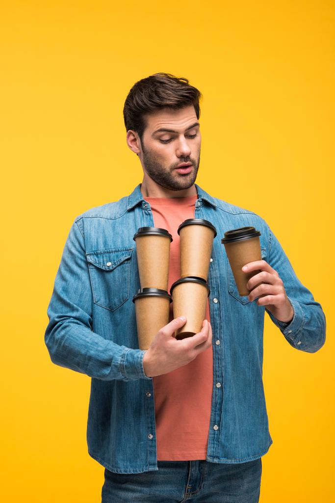 красавчик, держащий бумажные стаканчики с кофе, чтобы уйти в изоляцию на желтом
 - Фото, изображение