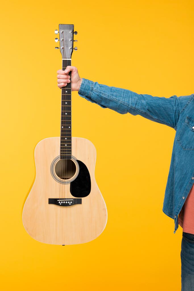 oříznutý pohled muže držící akustickou kytaru izolovanou na žlutém - Fotografie, Obrázek
