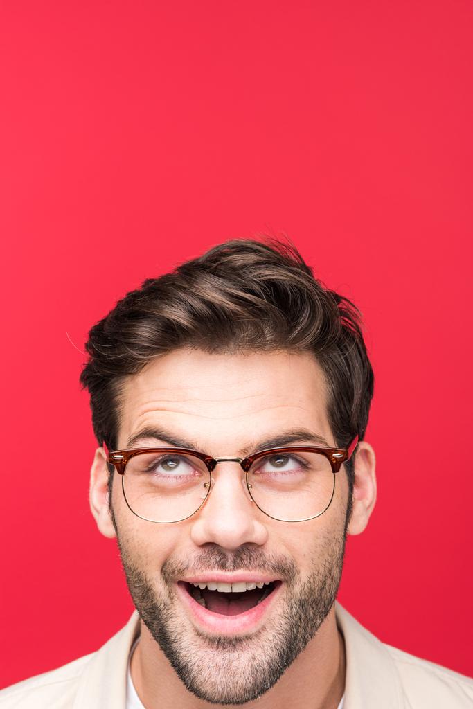 Yllättynyt komea mies silmälaseissa katselee ylös Eristettynä vaaleanpunaiseen
 - Valokuva, kuva