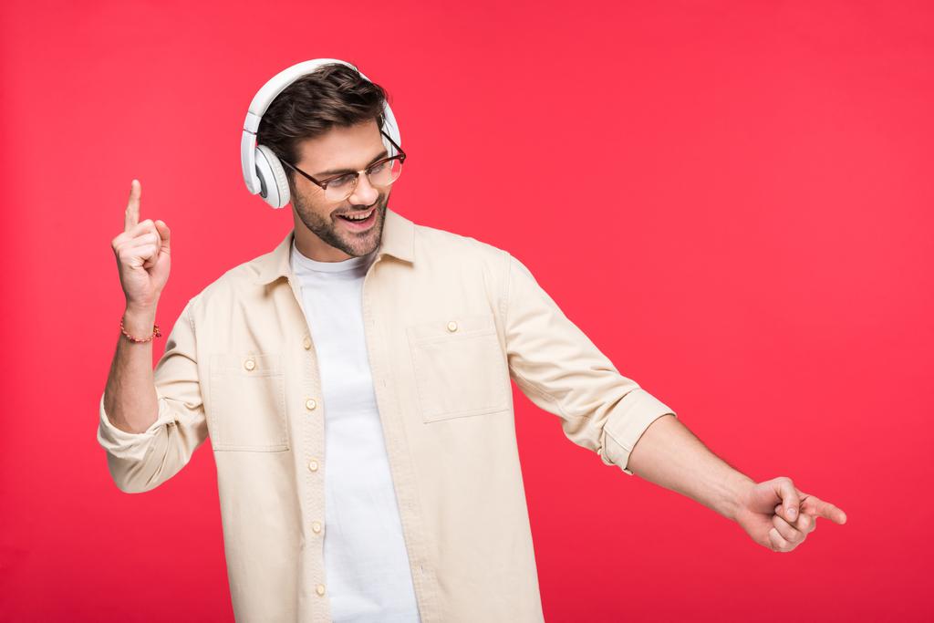 glücklicher gutaussehender Mann mit Kopfhörern, der mit Fingern auf rosa zeigt - Foto, Bild