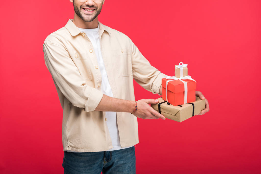 Vista recortada del hombre sonriente sosteniendo regalos en rosa
 - Foto, imagen