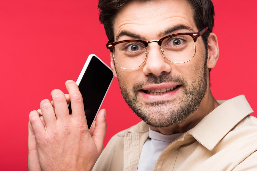 confused man talking on smartphone and looking at camera Isolated On pink - Photo, Image