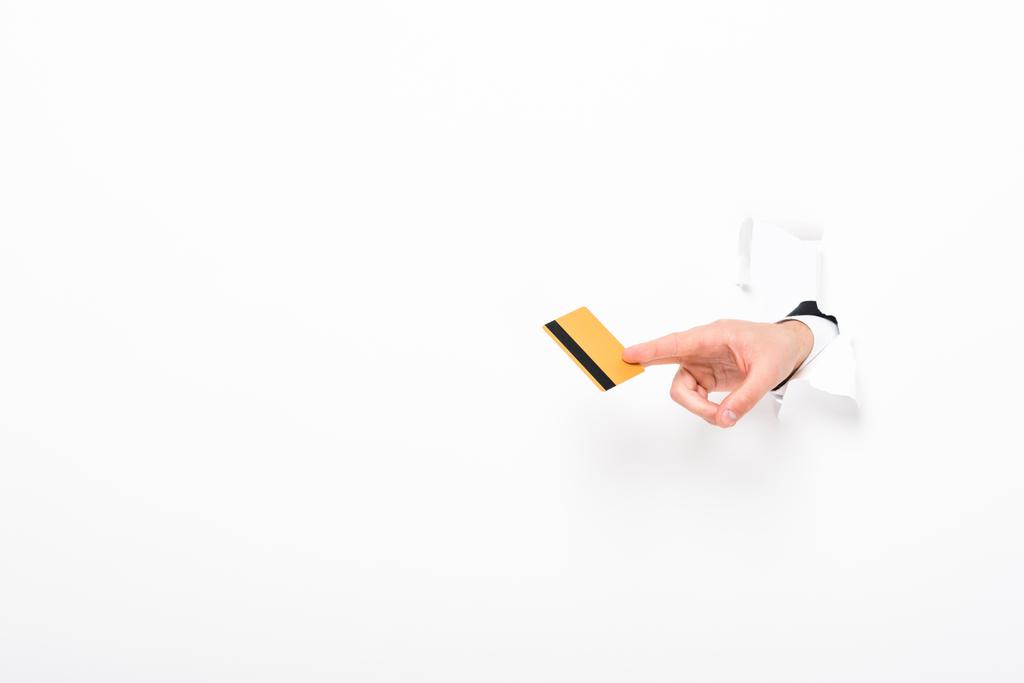 μερική όψη του ανθρώπου που κατέχει πιστωτική κάρτα από τρύπα στον τοίχο σε λευκό με χώρο αντιγραφής - Φωτογραφία, εικόνα