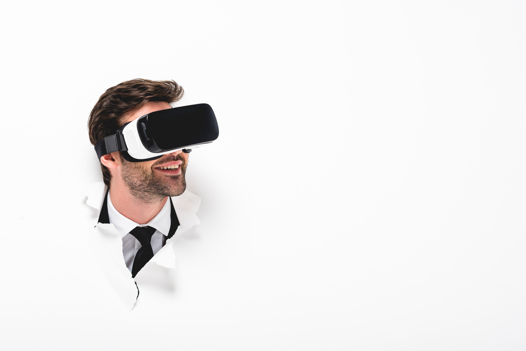 mosolygó férfi a virtuális valóság headset mögött lyuk a falon fehér és másolási tér - Fotó, kép