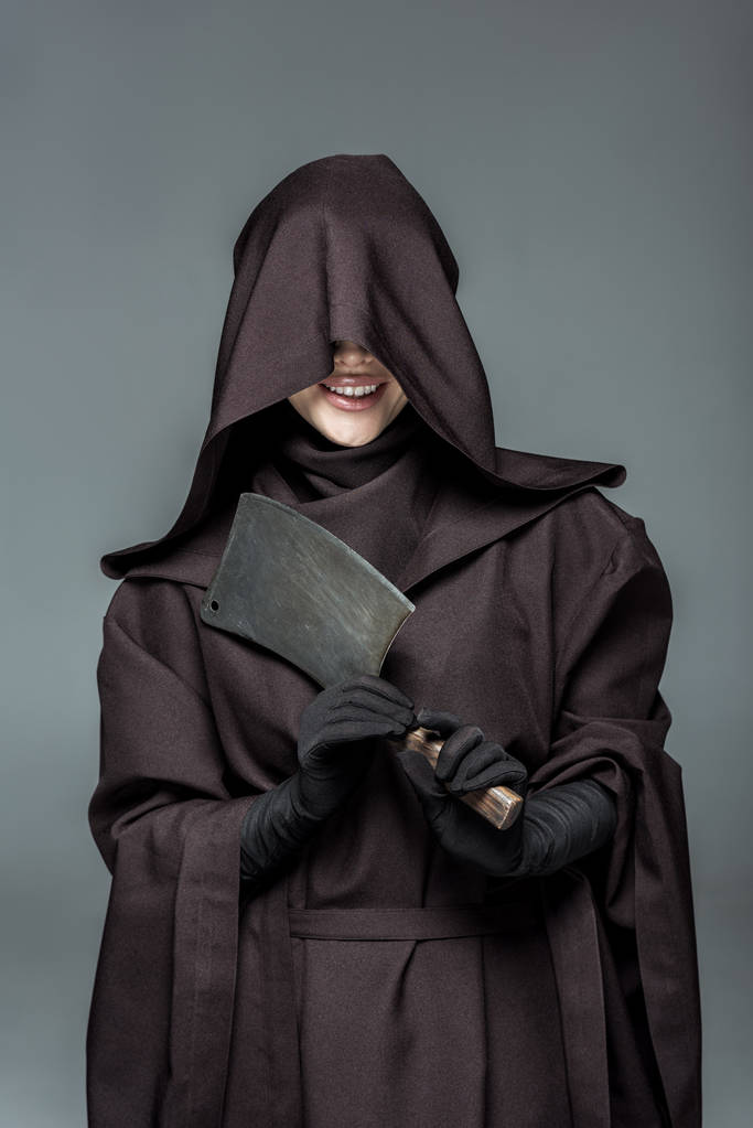 smiling woman in death costume holding cleaver isolated on grey - Photo, Image