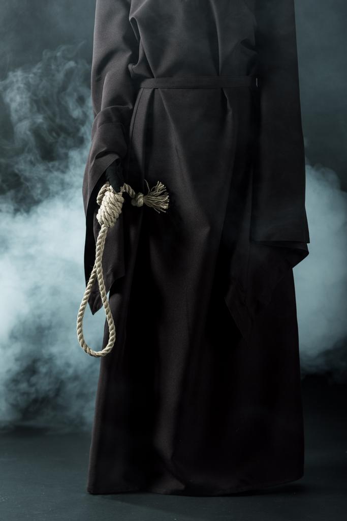 cropped view of woman in death costume holding hanging noose on black - Photo, Image