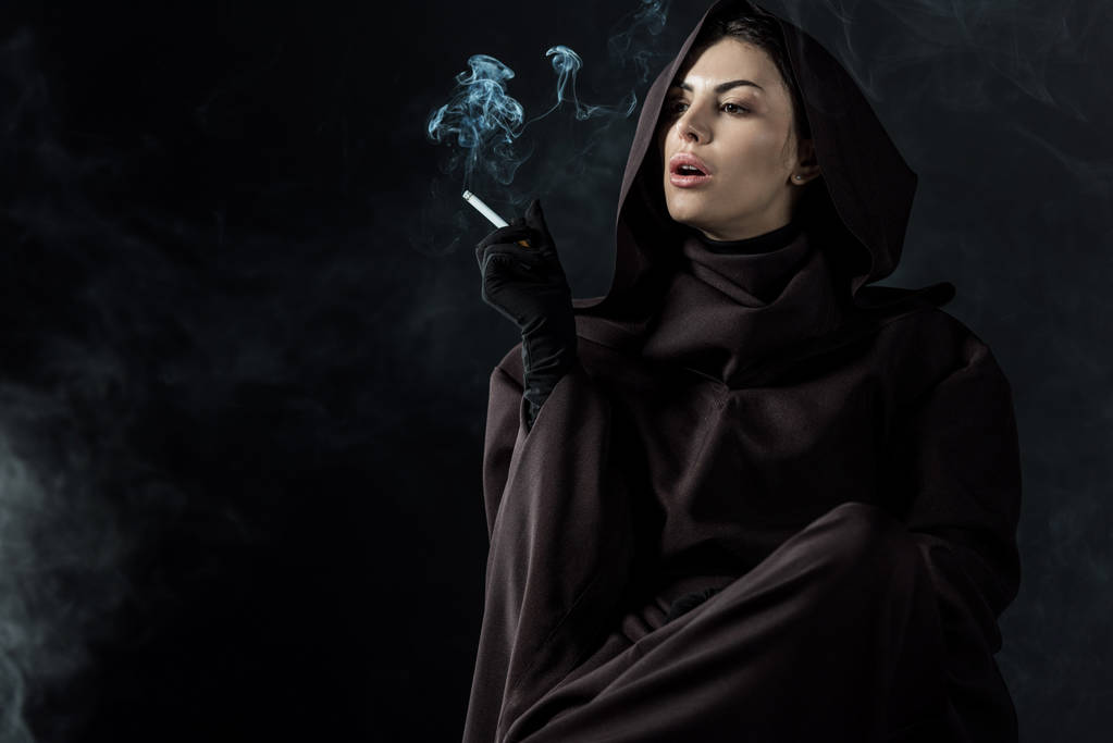 γυναίκα με στολή θανάτου καπνίζει τσιγάρο σε μαύρο - Φωτογραφία, εικόνα