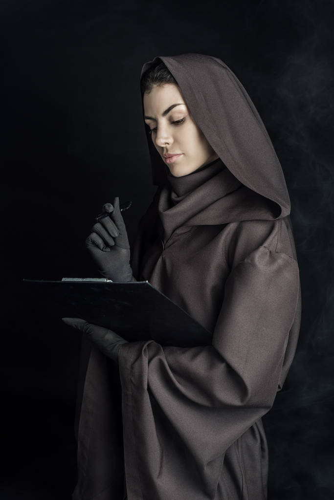 Frau im Todeskostüm hält Klemmbrett auf schwarz - Foto, Bild