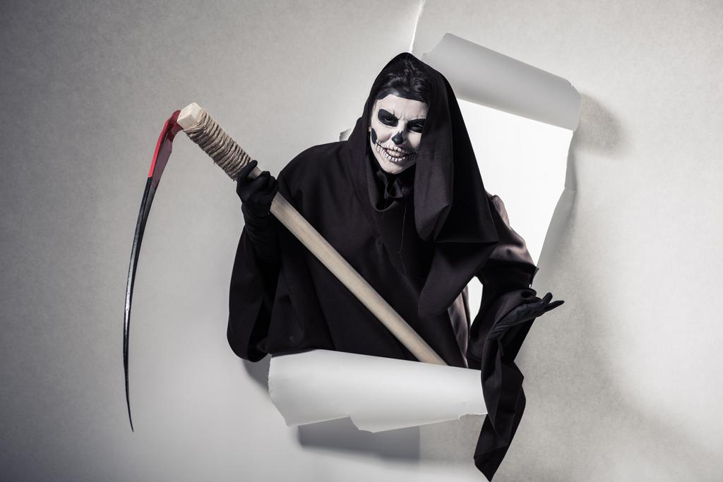 woman in death costume holding scythe and getting out of hole in paper - Photo, Image