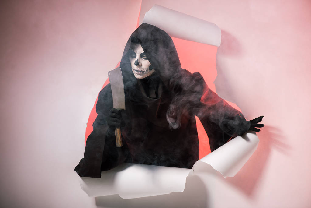 mujer en traje de la muerte sosteniendo cuchilla y salir del agujero en el papel
 - Foto, Imagen