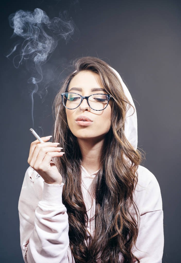 Рак лікує куріння. Гарненька жінка з довгим волоссям курить сигарету. Чуттєвий куріння наркоман або куріння. Жіночі звички куріння
 - Фото, зображення