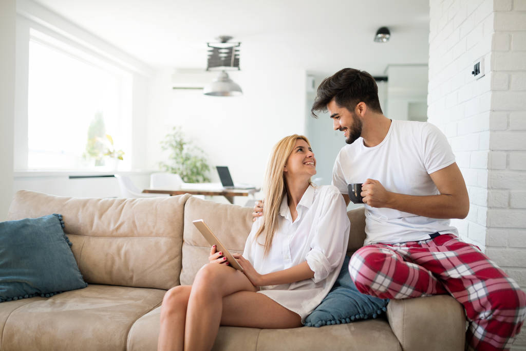 Mladý atraktivní pár spolu tráví čas doma pomocí tabletu - Fotografie, Obrázek