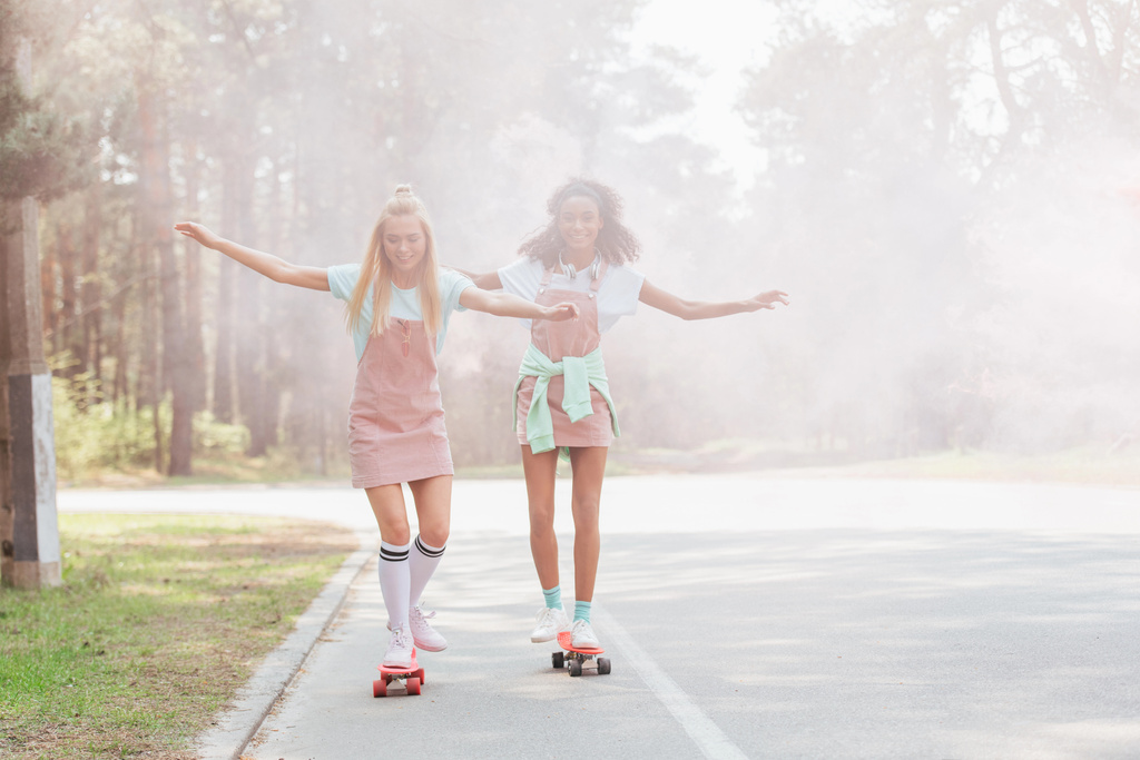 vista completa di due ragazze skateboard in fumo su strada
 - Foto, immagini