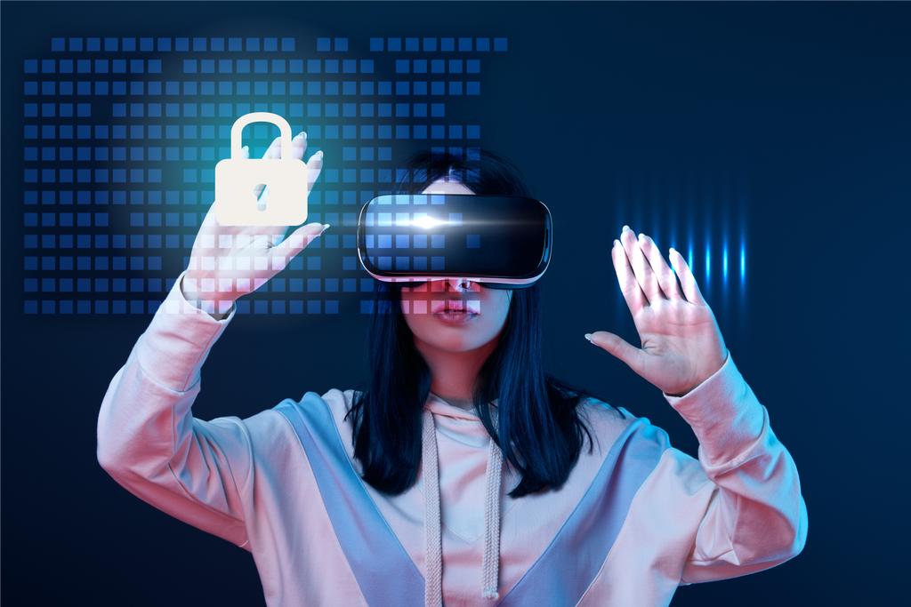 mladá žena ve virtuální realitě headset gestikulace mezi zářící kybernetické bezpečnosti ilustrace na tmavém pozadí - Fotografie, Obrázek