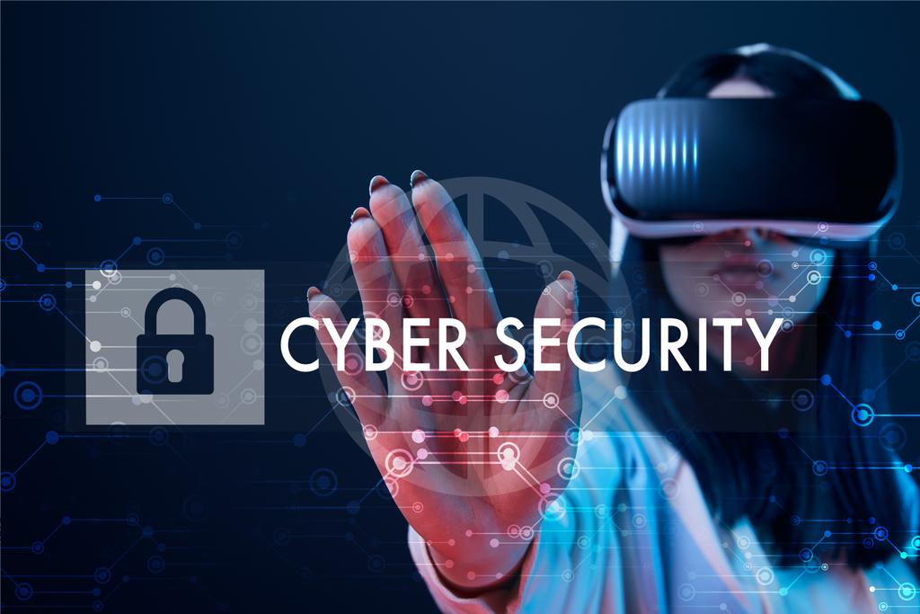 селективный фокус молодой женщины в гарнитуре виртуальной реальности, указывающей рукой на иллюстрацию кибербезопасности на темном фоне
 - Фото, изображение