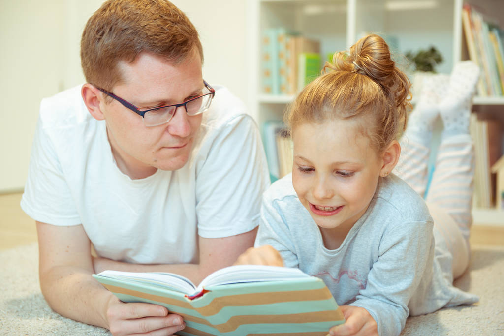 Young happy father reading book with  cute daughter at home - Photo, Image