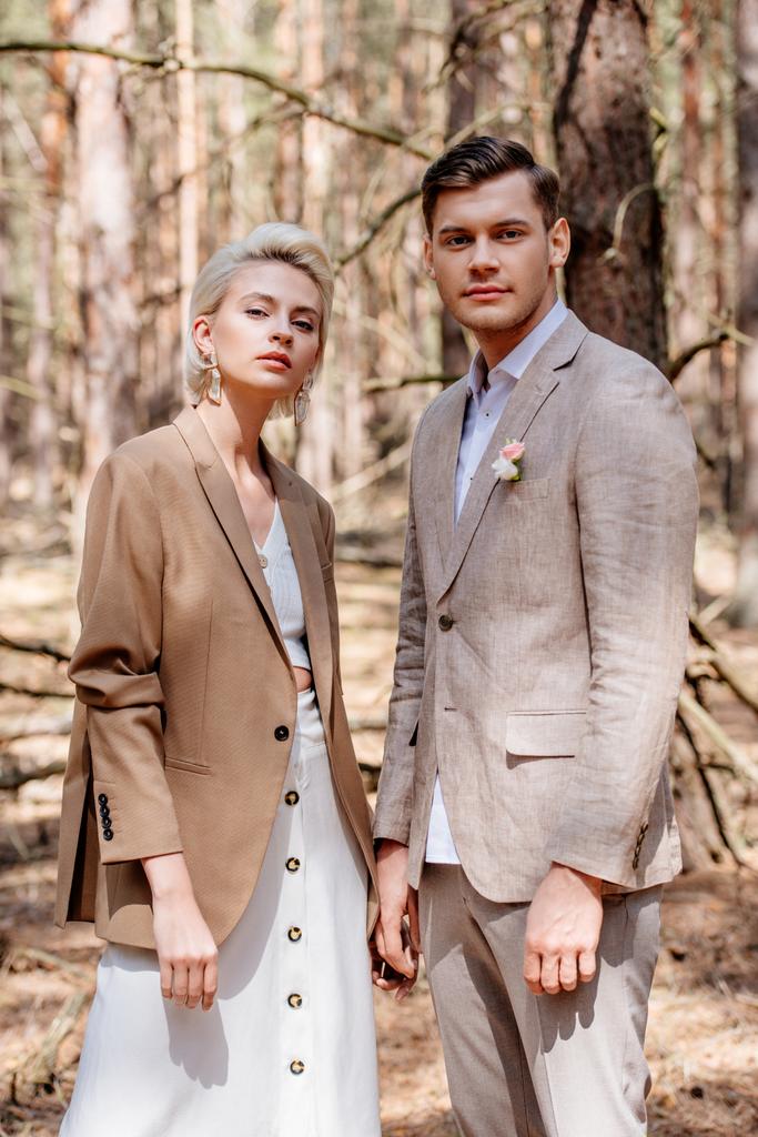 Novia y novio con estilo en ropa beige posando en el bosque
 - Foto, imagen