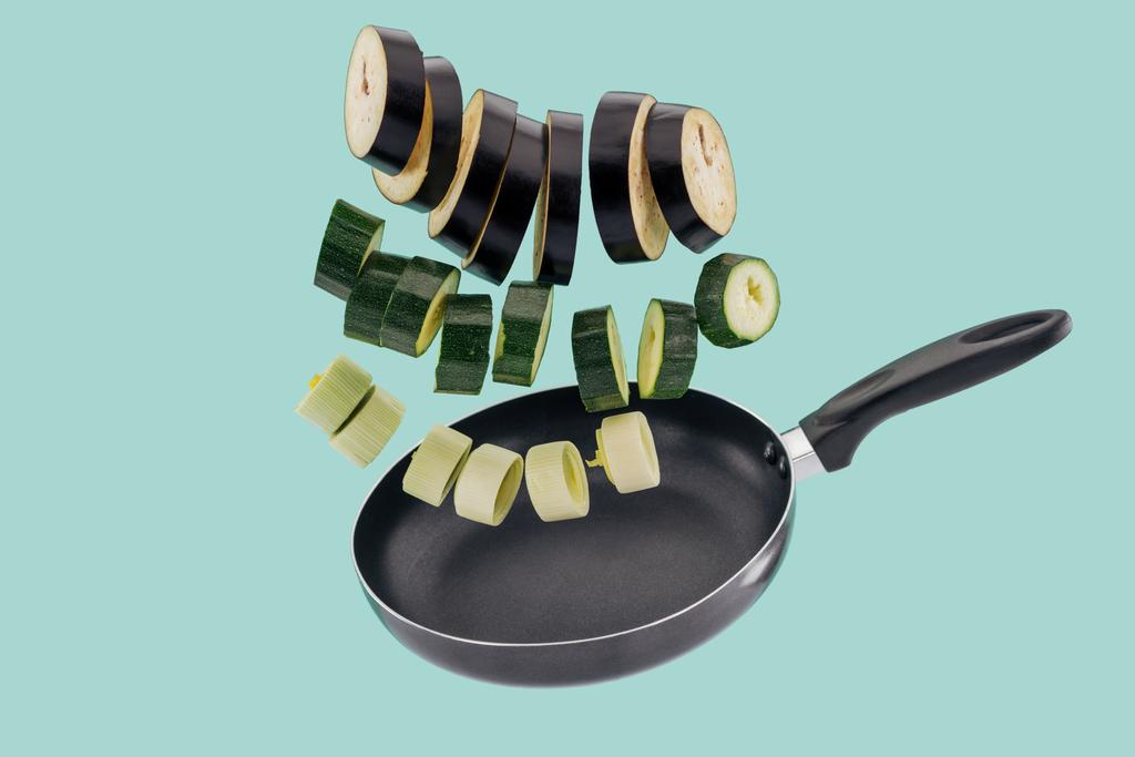 Sliced nutritious organic vegetables in frying pan isolated on turquoise  - Photo, Image