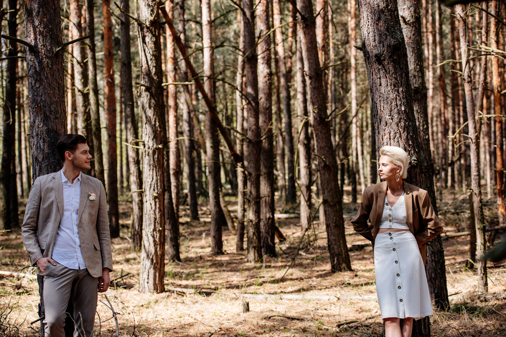 novia elegante y novio de pie en el bosque y mirándose el uno al otro
 - Foto, Imagen