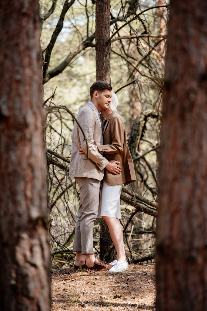 森の中で抱き合うエレガントなカップルの全長ビュー - 写真・画像