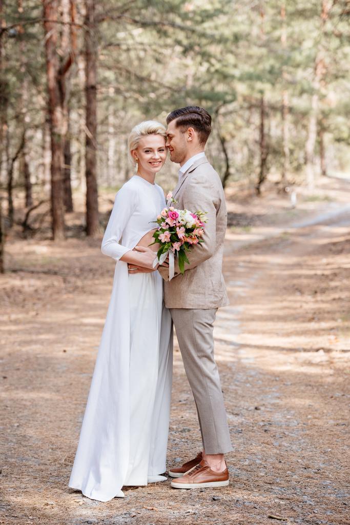 full length view of just married couple embracing in forest - Photo, Image