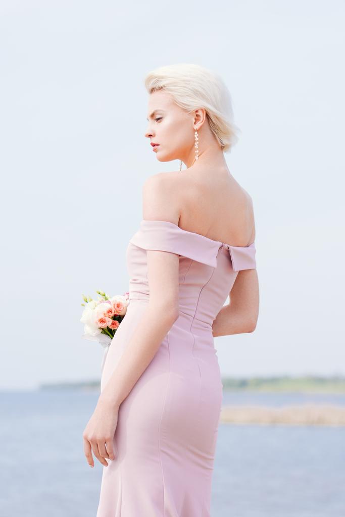 花束を持つピンクのドレスでペンシブブロンドの女の子 - 写真・画像