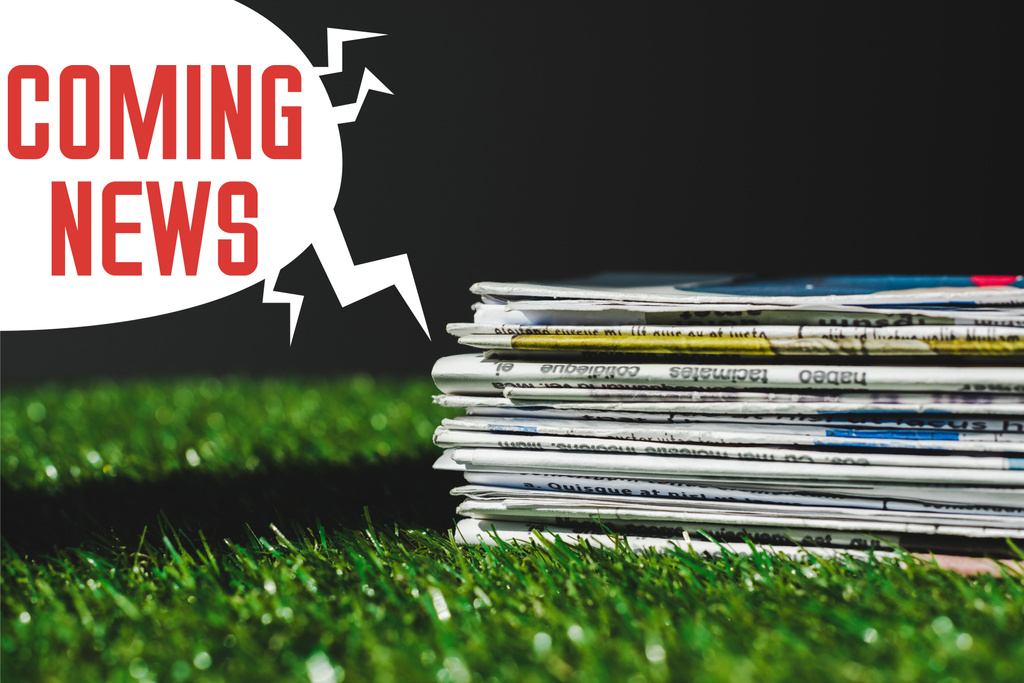 赤い来るニュースレタリングが黒で隔離されたスピーチバブルの近くの新鮮な緑の草の上に異なる印刷新聞のスタック - 写真・画像