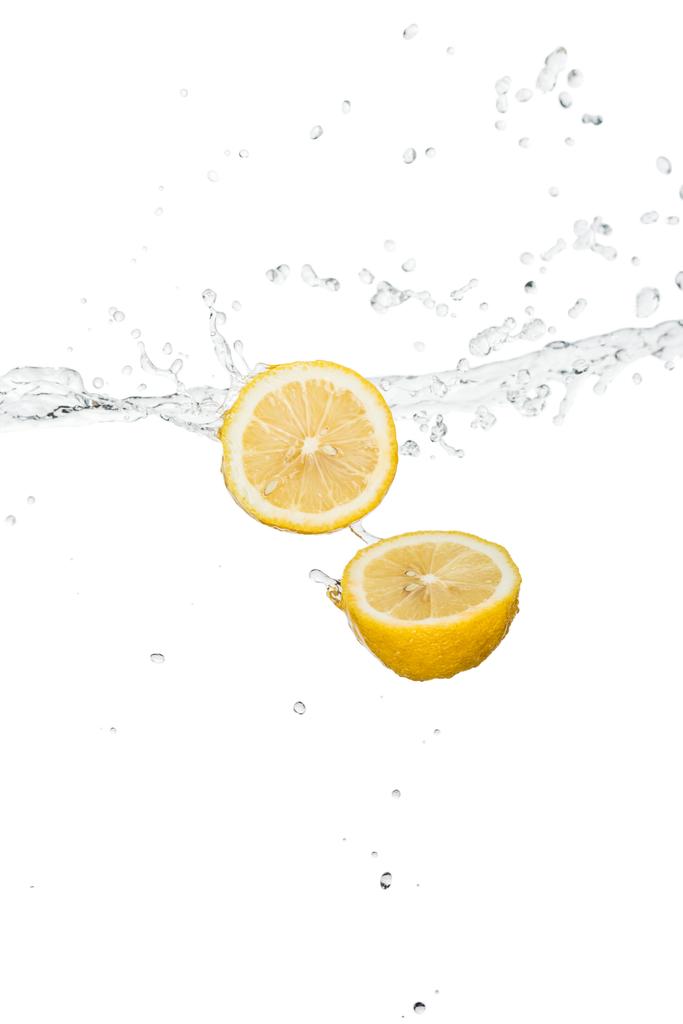 黄色のレモンの半分に澄んだ水のスプラッシュと白で隔離された滴 - 写真・画像