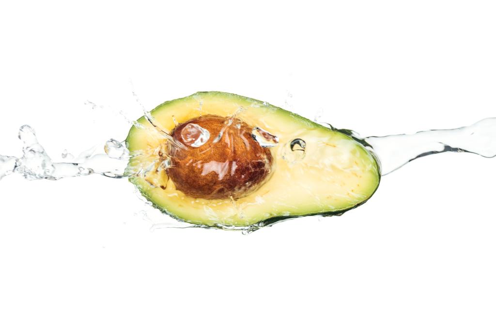 ripe nutritious avocado with seed and transparent water stream isolated on white  - Photo, Image