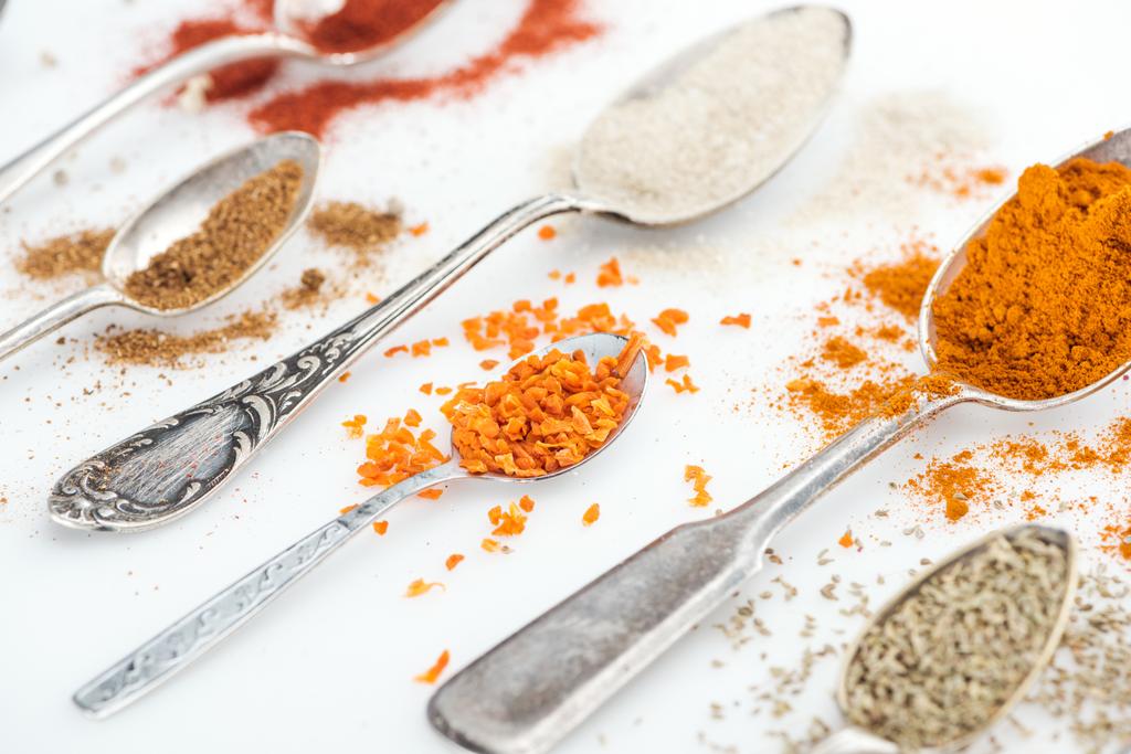 close up view of various colorful spices in silver spoons on white background - Photo, Image