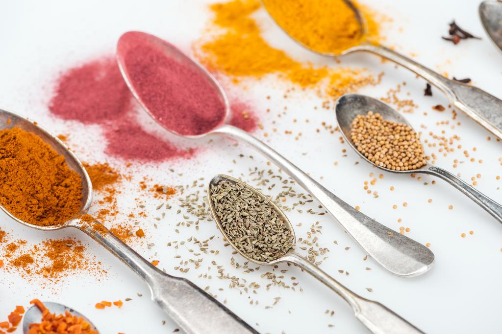 close up view of various spices in silver spoons on white background - Photo, Image