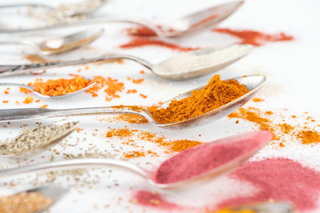 valikoiva painopiste värikkäitä kirkkaita mausteita hopealusikoita valkoisella pohjalla
 - Valokuva, kuva