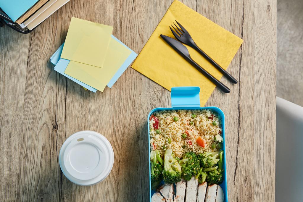 Ahşap masa üzerinde risotto ve tavuk ile yapışkan notlar ve sağlıklı lezzetli öğle yemeği ile işyeri üst görünümü - Fotoğraf, Görsel