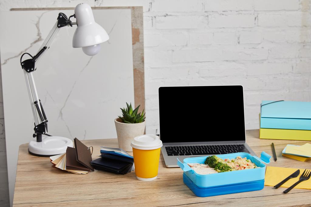 blaue Lunchbox aus Kunststoff mit gesundem Essen auf Holztisch mit Laptop und Sukkulente auf weißem Hintergrund, illustrativer Leitartikel - Foto, Bild
